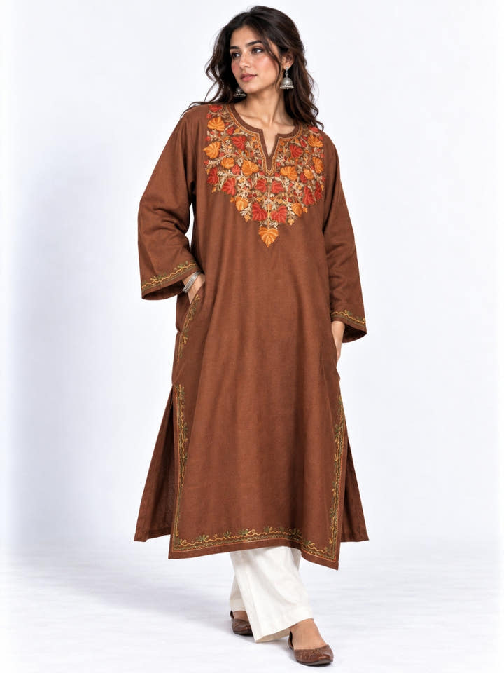 A woman in a brown Kashmiri pheran with an embroidered neck, wide embroidered cuffs, side slits and a border at the hem, KAARKASH